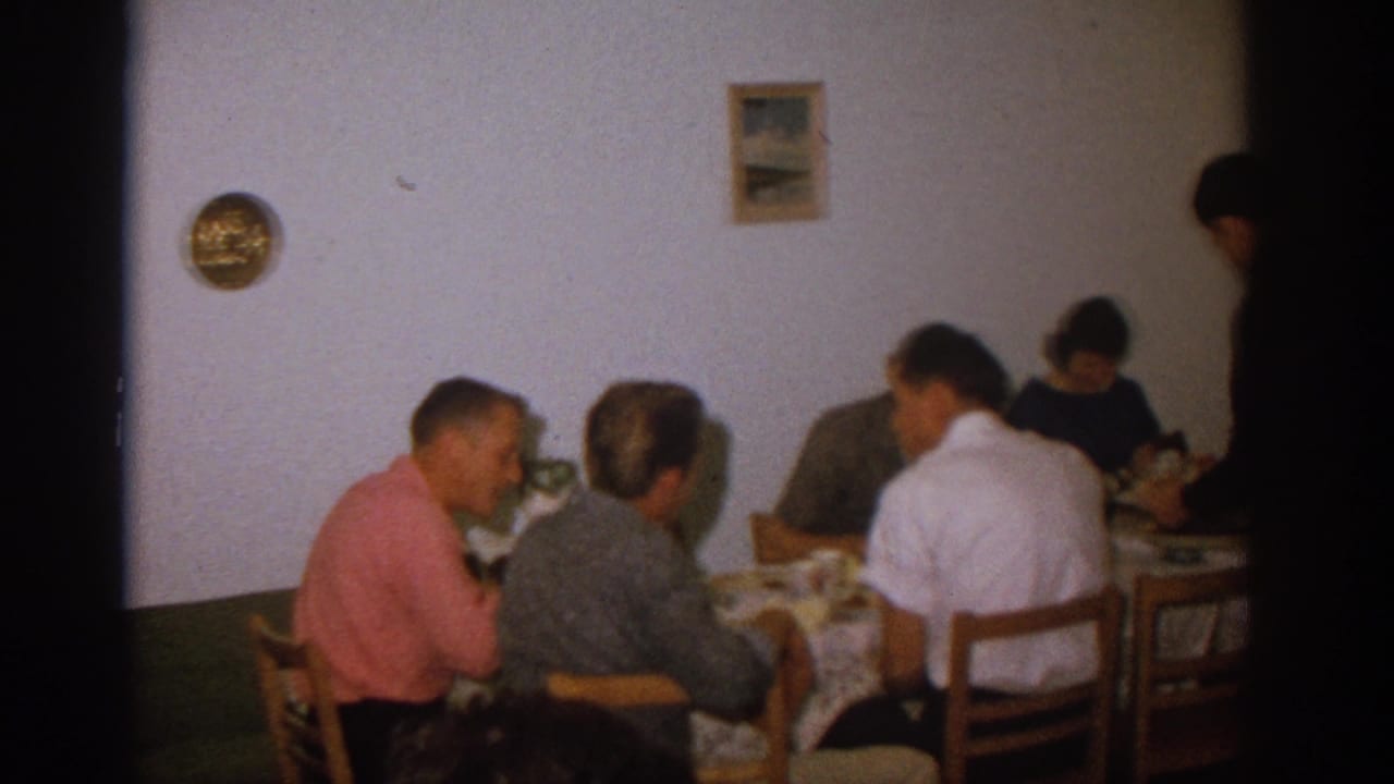 Adults seated around a dining table in a modest room.