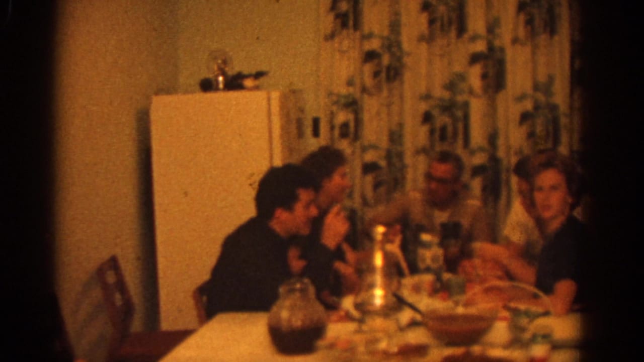 Several adults eat and talk around a table with dishes and glasses.