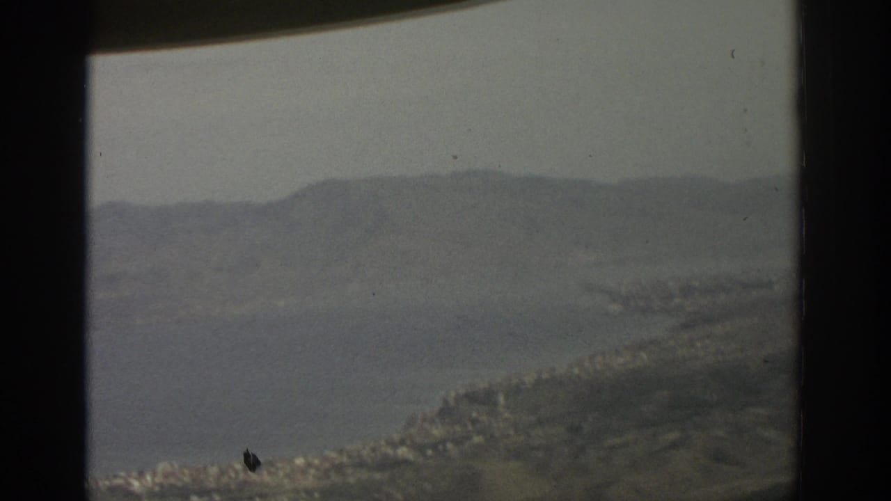 Lake shoreline and mountain ridge viewed from behind a vertical window divider.
