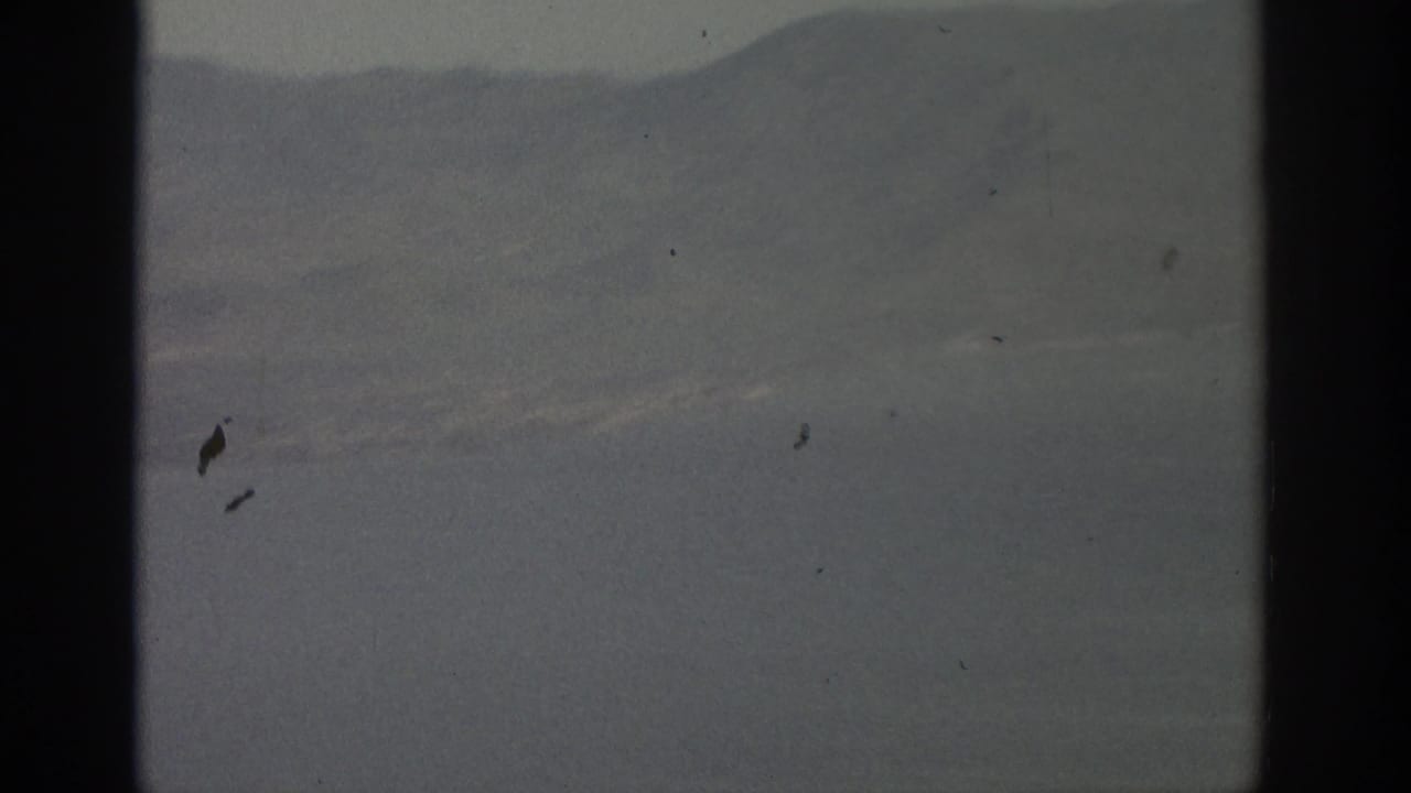 1963 8mm view near Zurich showing hazy mountains and water through an aircraft window frame.