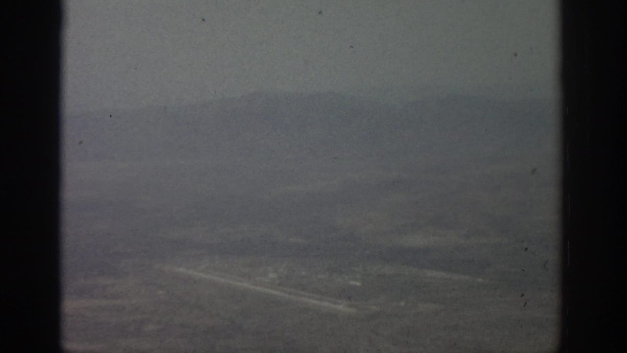 Dim aerial view of terrain and roads through a divided window.