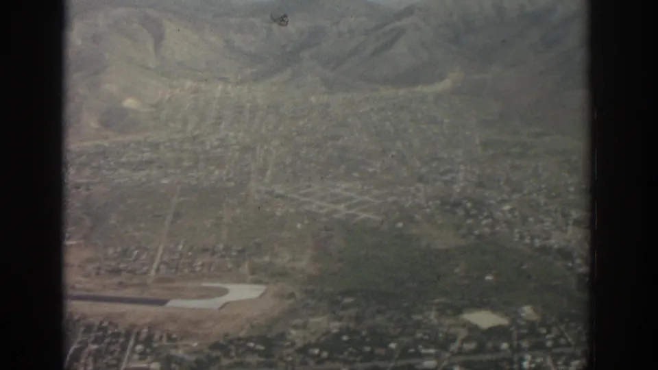 Late clip frame from the 1963 Zurich aerial view, with a dark window divider over city grid, hills, and open ground.