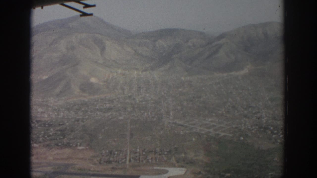 Hazy aerial view of a mountain valley city with part of an airplane wing visible.