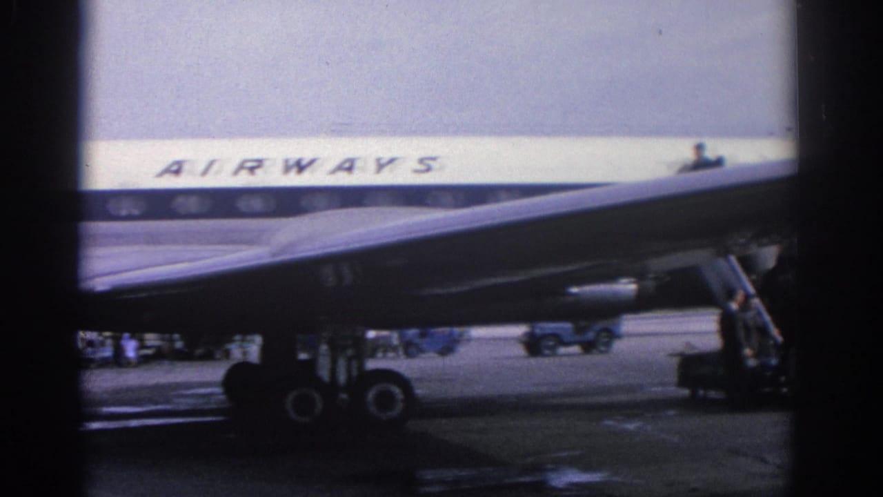 1963 Zurich airport footage showing part of an Olympic Airways plane, mobile stairs and figures near the tarmac.
