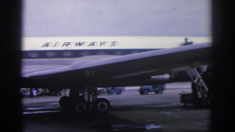 1963 Zurich airport footage showing part of an Olympic Airways plane, mobile stairs and figures near the tarmac.