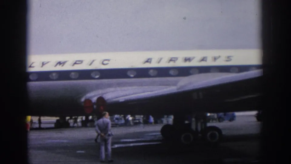 Olympic Airways aircraft at Zurich airport in 1963, with passengers or crew near stairs and ground equipment.
