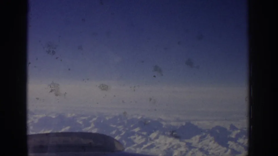 Aerial view of alpine-looking mountains from a passenger window in 1963 Zurich-linked travel footage.
