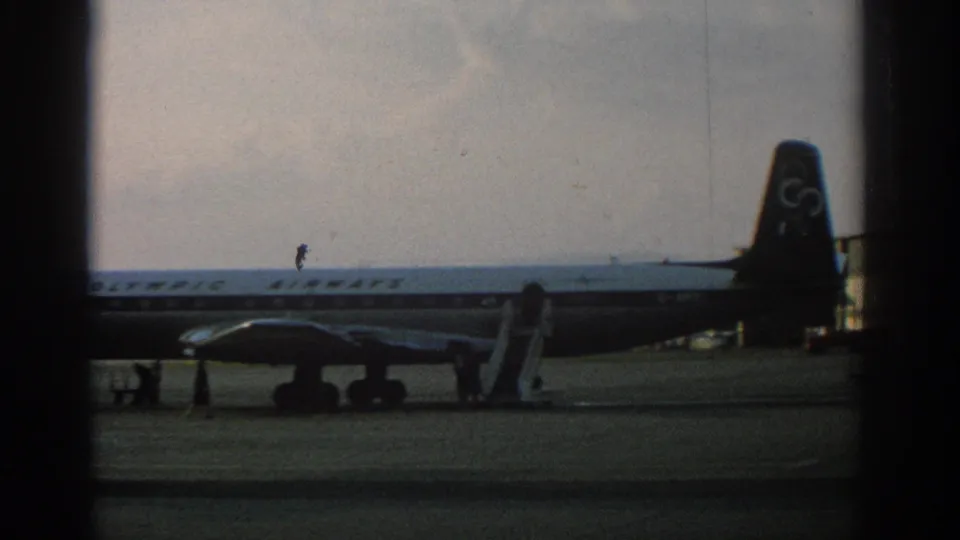 Closer 1963 Zurich view of the Olympic Airways aircraft tail, engine, landing gear, and boarding stairs.