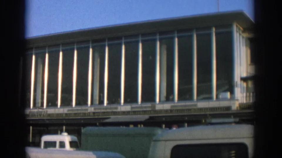 Zurich 1963 view of a modernist building with reflective glass panels and partial vans along the street.