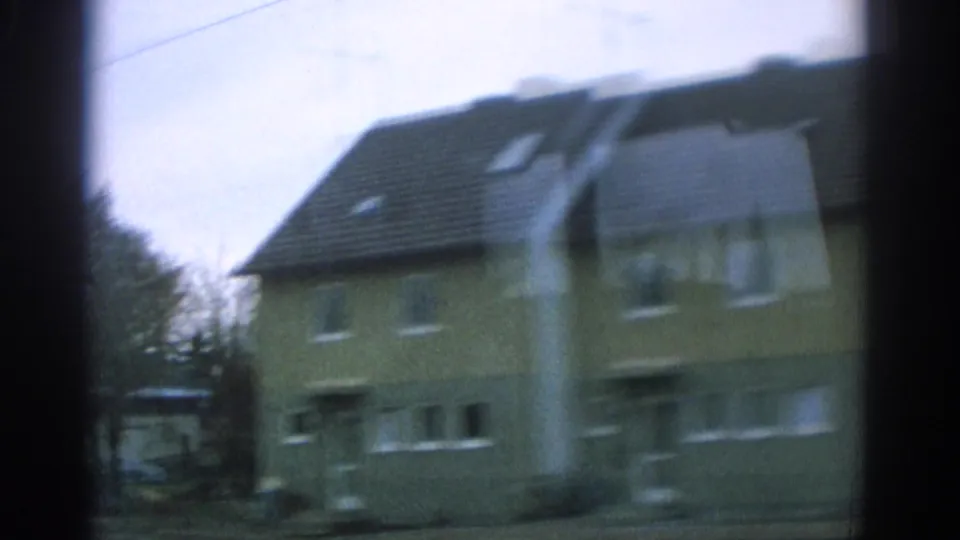 Motion-blurred 1963 Zurich-area residential view, with a steep-roofed house passing the camera near the end of the clip.