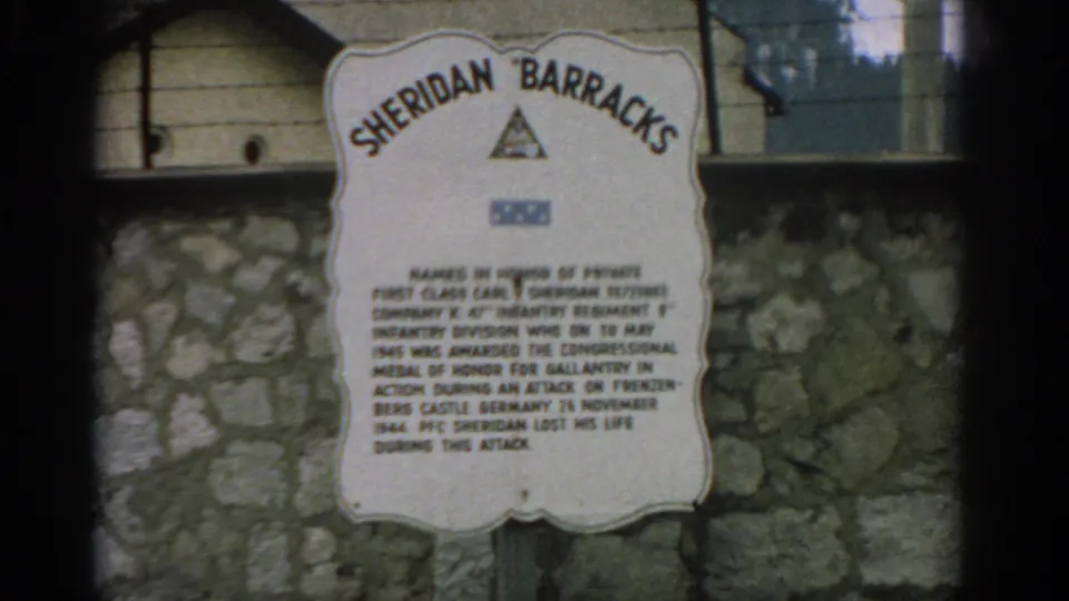 1963 Switzerland 8mm frame showing a Sheridan Barracks memorial plaque on a stone wall with military insignia above the text.