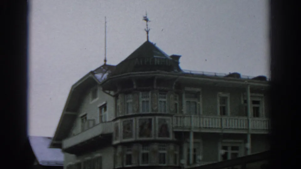 1963 8mm frame showing the ALPENHOF building facade with balconies, painted panels, and multiple windows.