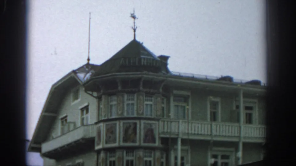 Wider 1963 Zurich frame of the ALPENHOF hotel facade with corner bay, painted lower panels, balcony, and roof ornament.