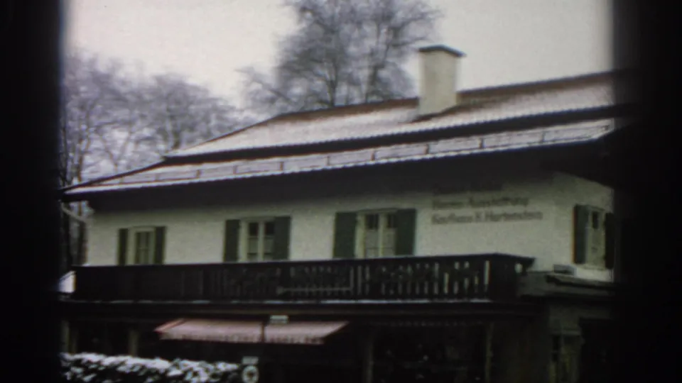 1963 Zurich 8mm frame showing a snowy Alpine-style building facade with green shutters, a dark balcony, and German wall lettering.