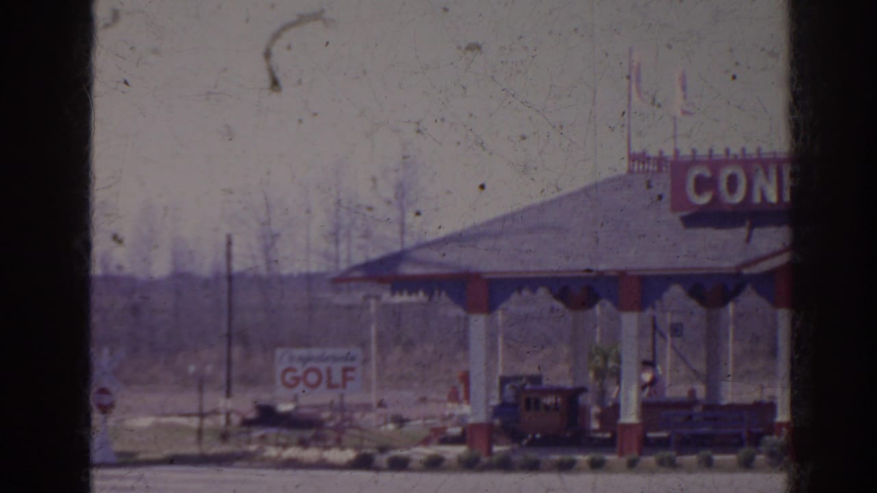 Covered roadside pavilion with partial CONFEDERATE sign, golf sign, and small train under the roof.