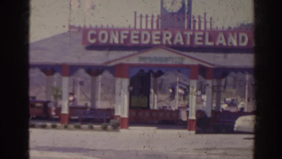 1962 Florida home-movie frame showing the Confederateland entrance sign and ticket booth from outside the attraction.