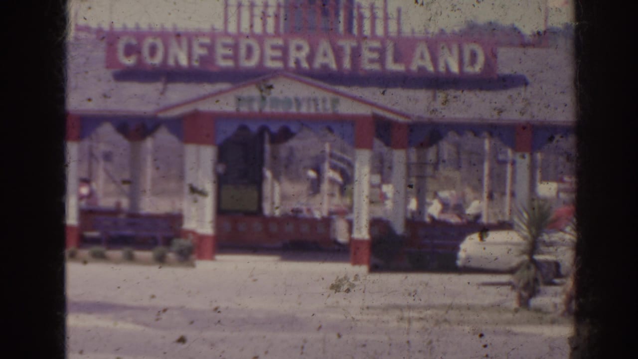 Confederateland entrance with ticket booth, train display, and a visitor nearby.