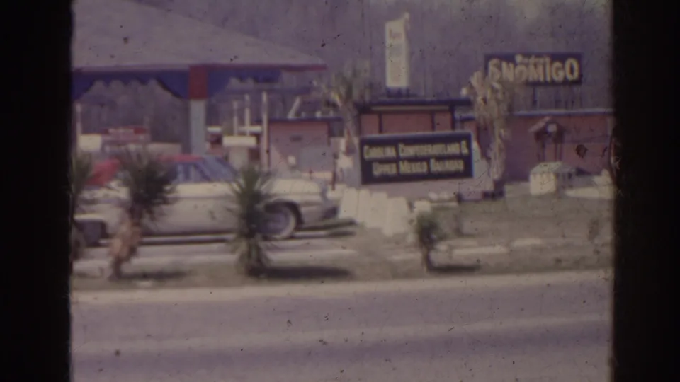 1962 Florida roadside frame showing a parked car, Confederateland attraction sign, and Six Gun style signage near the entrance area.