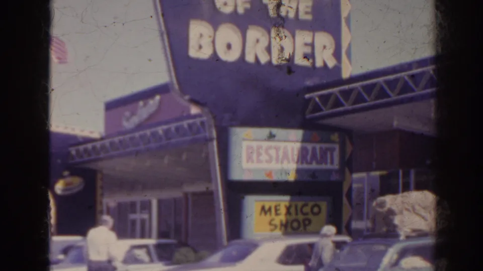 1962 Florida roadside view showing South of the Border signage, restaurant and Mexico Shop signs, parked cars, and distant people near the storefront.