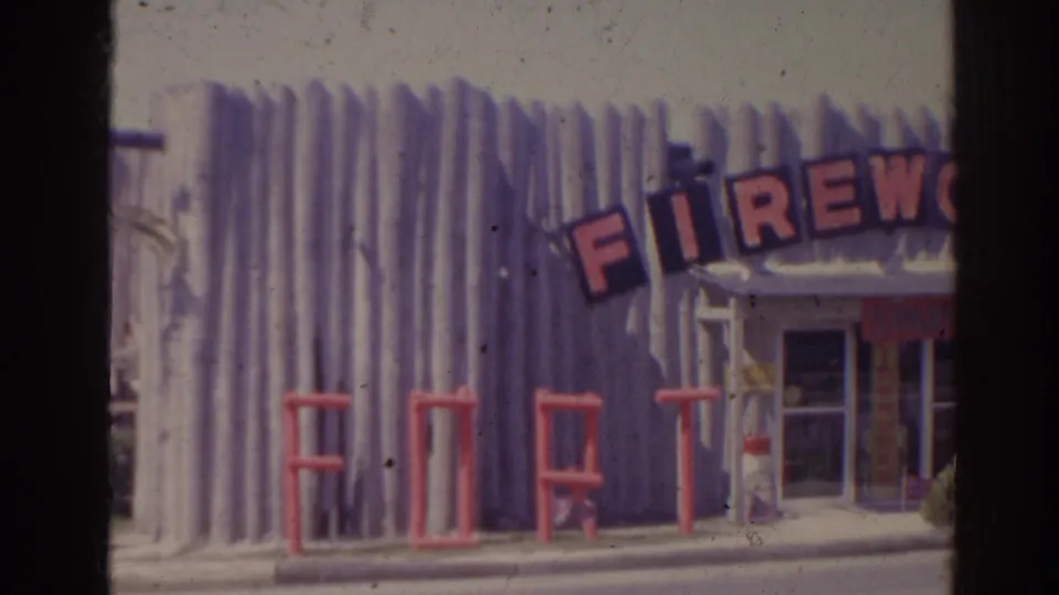 1962 Florida home-movie frame with a closer view of a novelty roadside building, partial FIREWORK lettering, and large FORT letters.