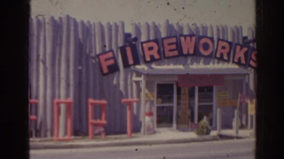 1962 Florida home-movie frame showing a roadside fireworks store with a large red arched sign and corrugated metal facade.