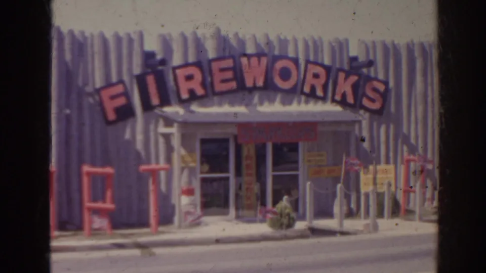 1962 Florida frame of a fireworks storefront, with bold red signage above the doors and smaller signs around the entrance.