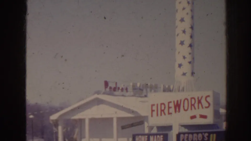 1962 Florida 8mm frame showing a white gabled roadside building, Fireworks lettering, Pedro signage, and a tall star-patterned rotating sign.