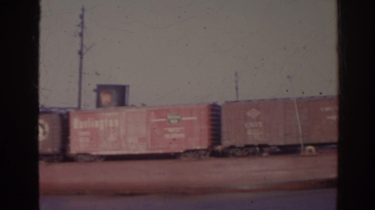 Freight cars stretch across a barge with a vertical film border at left.