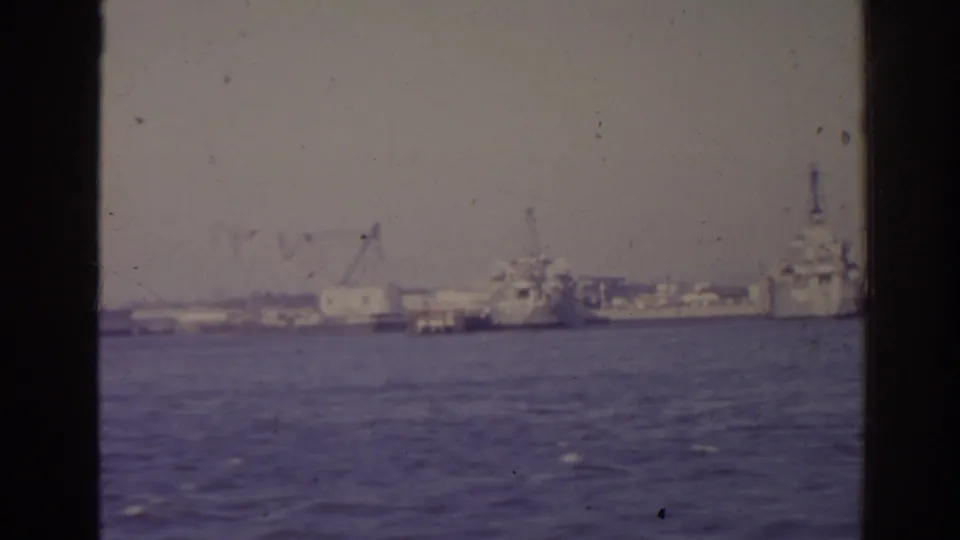 1962 Florida harbor pan showing open water, industrial docks, cranes, and large naval-looking vessels moored along the far shoreline.