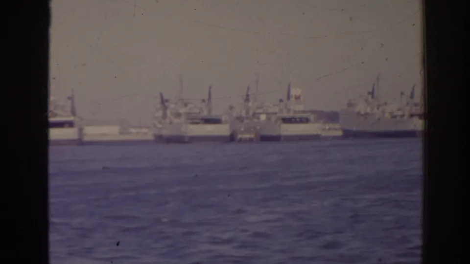 1962 Florida 8mm frame showing distant large ships and masts across open water under a hazy sky.
