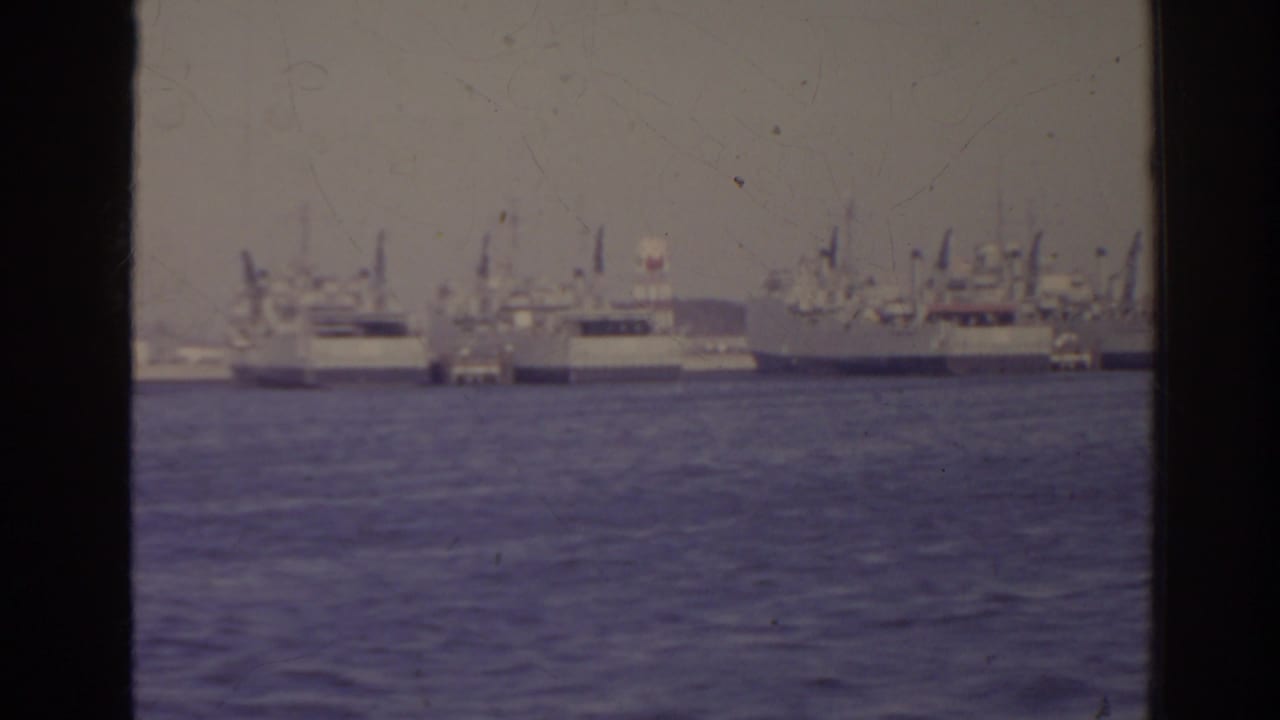 Large ships and harbor structures seen across the water.