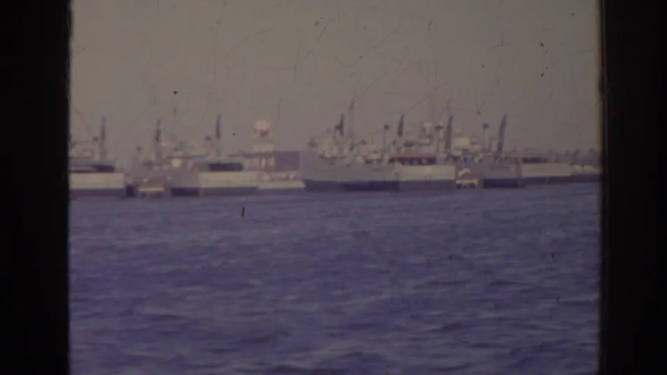 1962 Florida 8mm still with several distant vessels, mast lines, and a waterfront seen over rippling water.