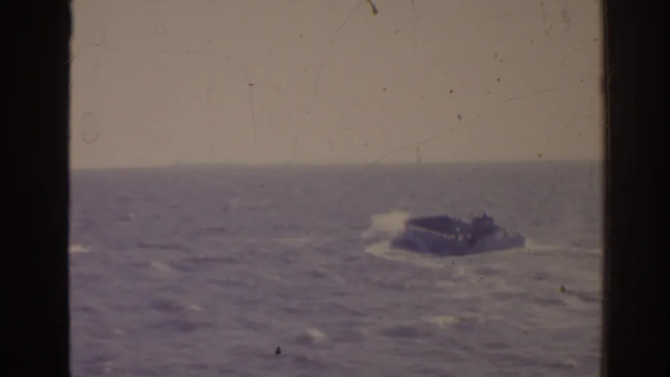 1962 Florida 8mm frame showing a small military-style craft in rough seas with white spray and faded color.