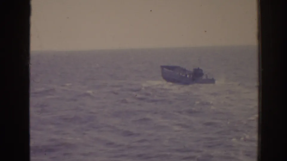 Distant small craft on rough Florida seas, framed by dark 8mm film borders and faded 1960s color.