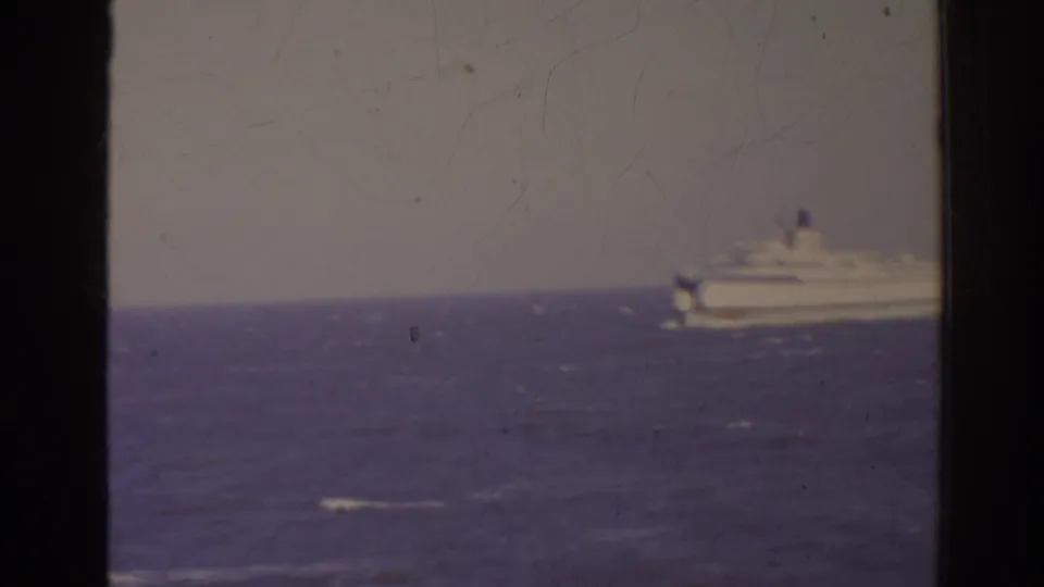 1962 Florida home-movie frame with a distant passenger ship or ferry on the horizon across choppy water.
