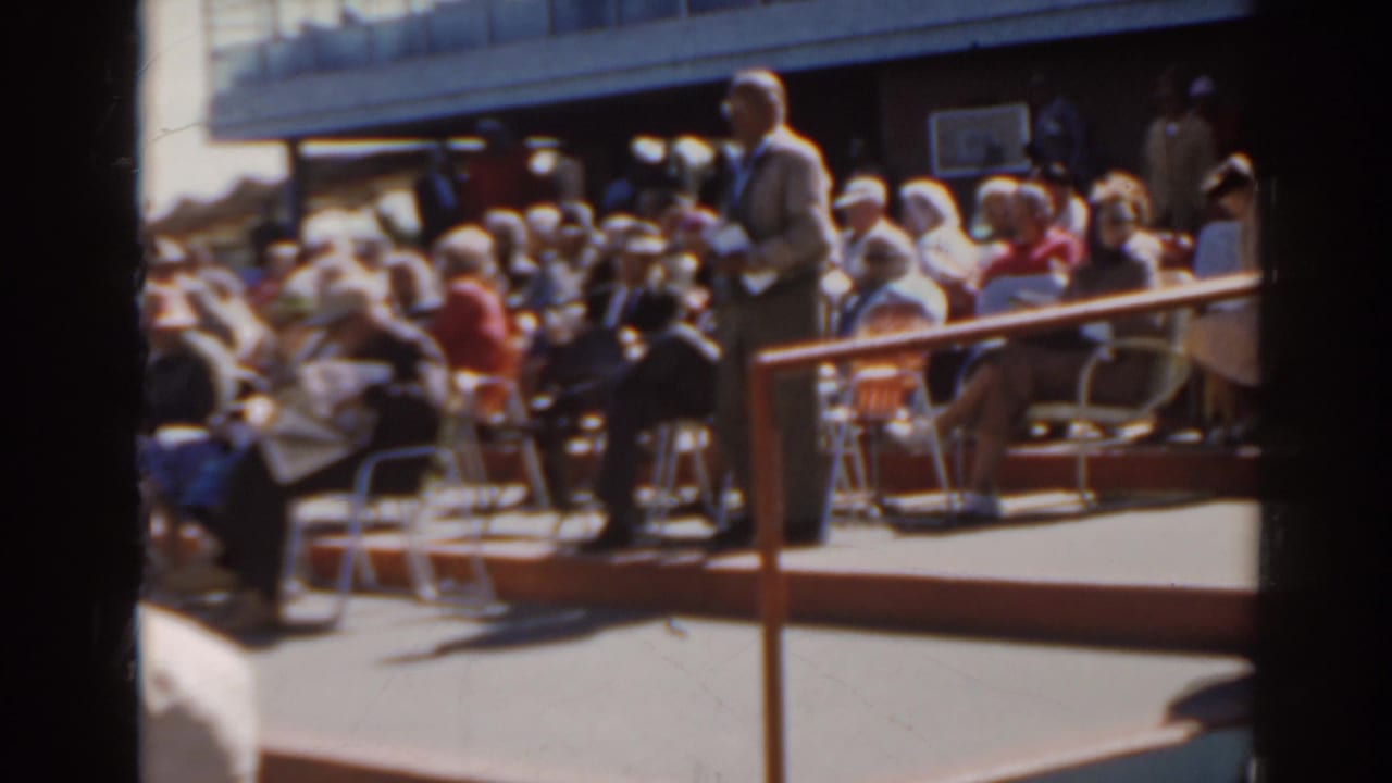 Home-movie view of a 1962 Florida racetrack crowd seated in folding chairs near the rail.