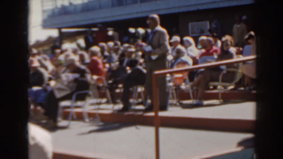 Home-movie view of a 1962 Florida racetrack crowd seated in folding chairs near the rail.