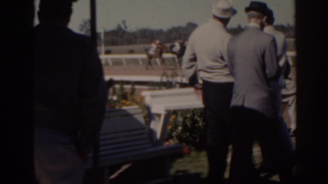 1962 Florida home-movie view of spectators in formal dress watching horses race along a dirt track.