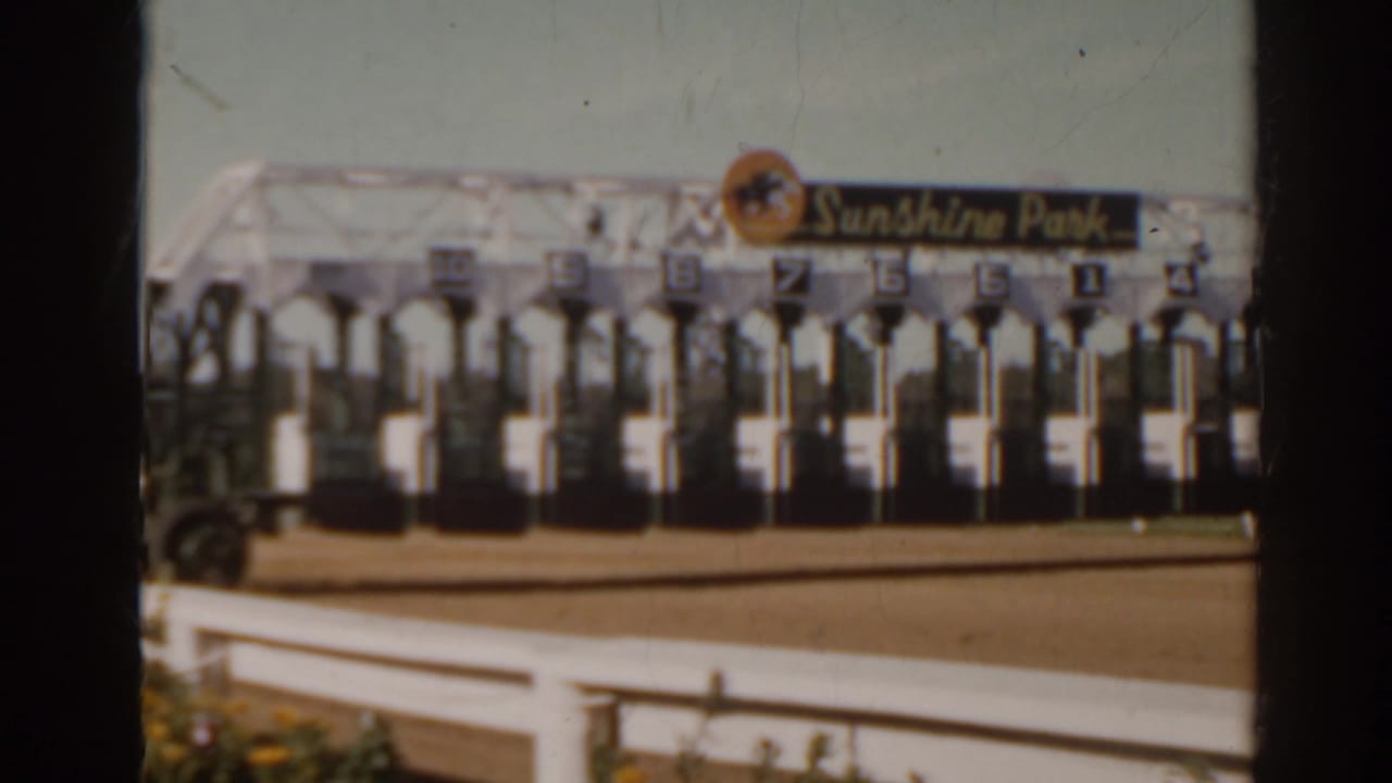 Sunshine Park starting stalls with numbered gate positions, seen in faded 8mm color at the racetrack.