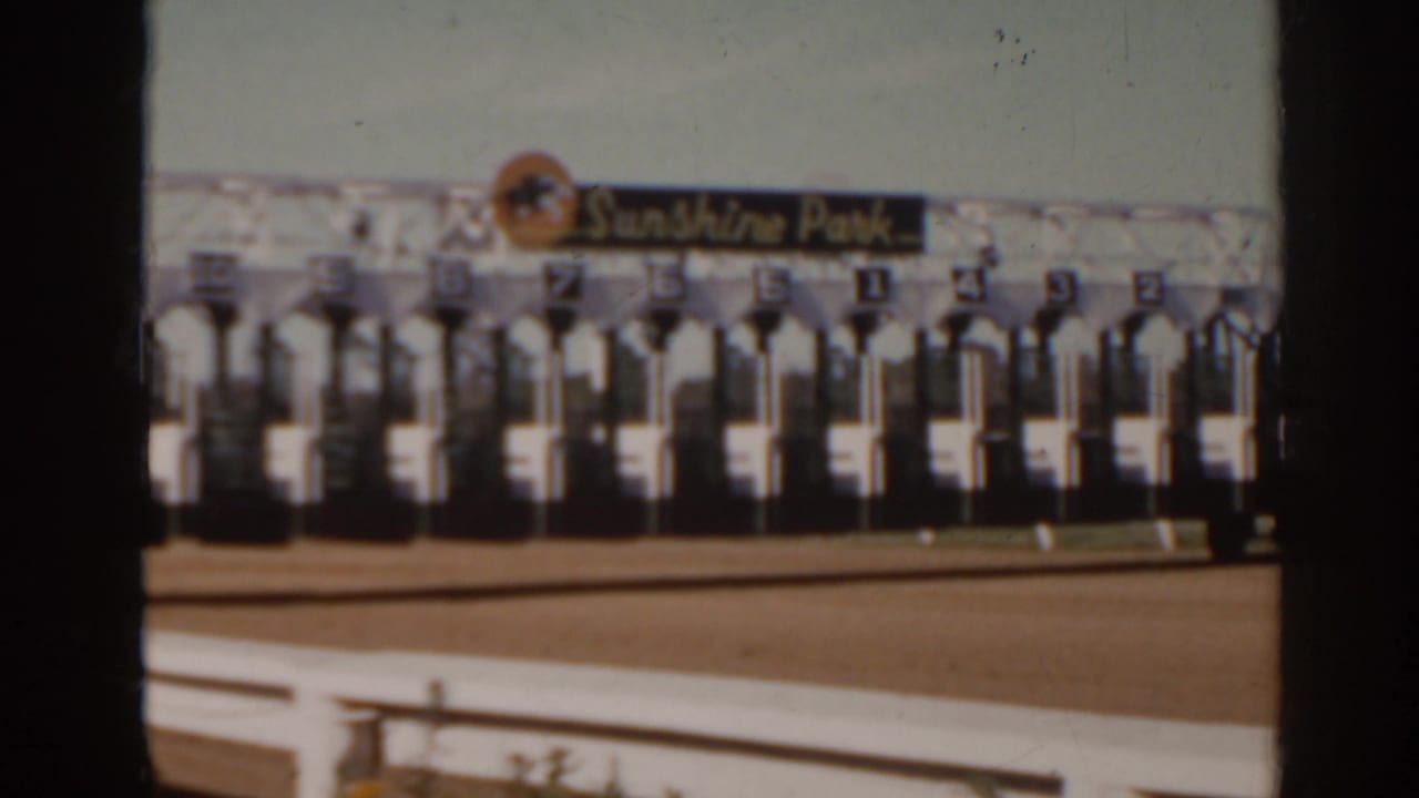 The racetrack starting gate line and Sunshine Park sign remain visible beyond a white rail in 1962 Florida footage.