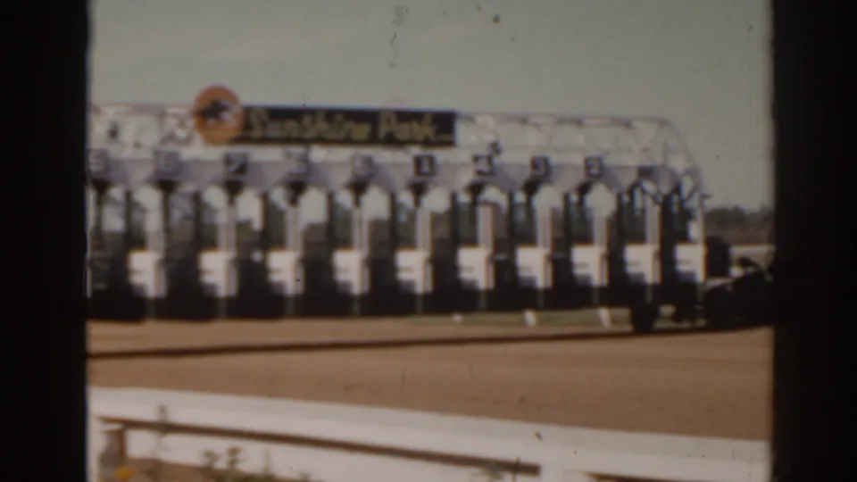 1962 Florida home-movie frame showing numbered starting stalls at Sunshine Park racetrack beside a dirt course.
