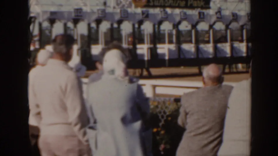 1962 Florida racecourse frame showing spectators from behind and the Sunshine Park starting gates across the track.