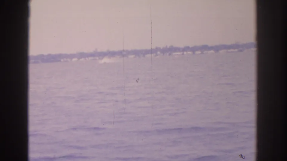 1962 Florida home-movie frame of a hazy water view with a distant shoreline and visible 8mm film artifacts.