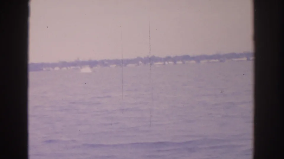 1962 Florida home-movie frame with rippled water, a far shoreline, and faded color from the 8mm scan.