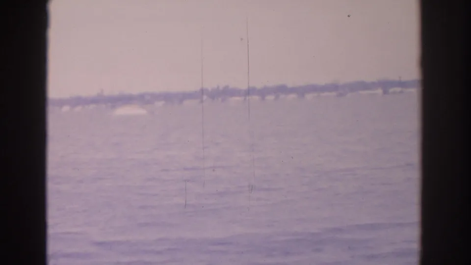 1962 Florida 8mm frame showing open water, a faint shoreline, hazy sky, and dark contact-sheet borders.