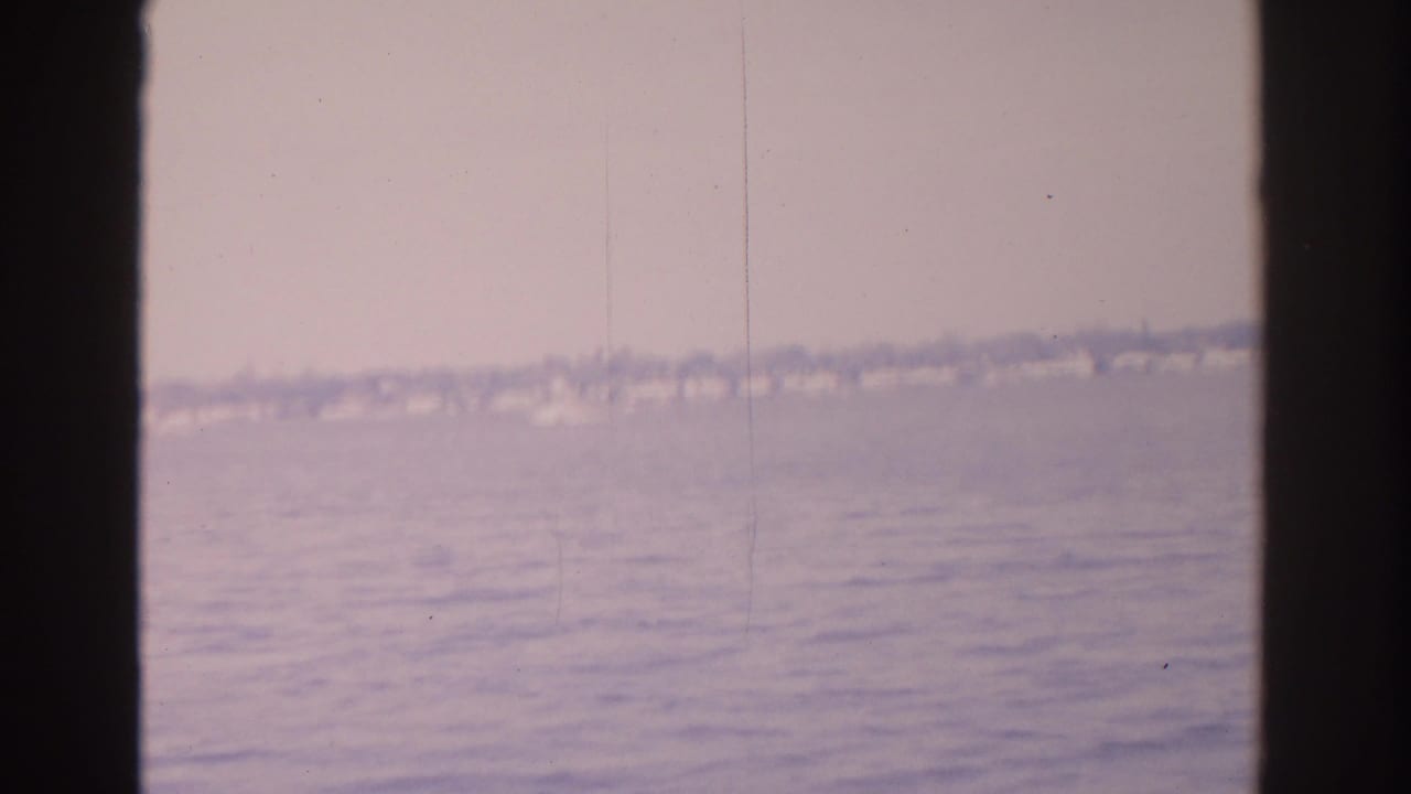 Distant shoreline and rippled water framed by dark vertical edges.