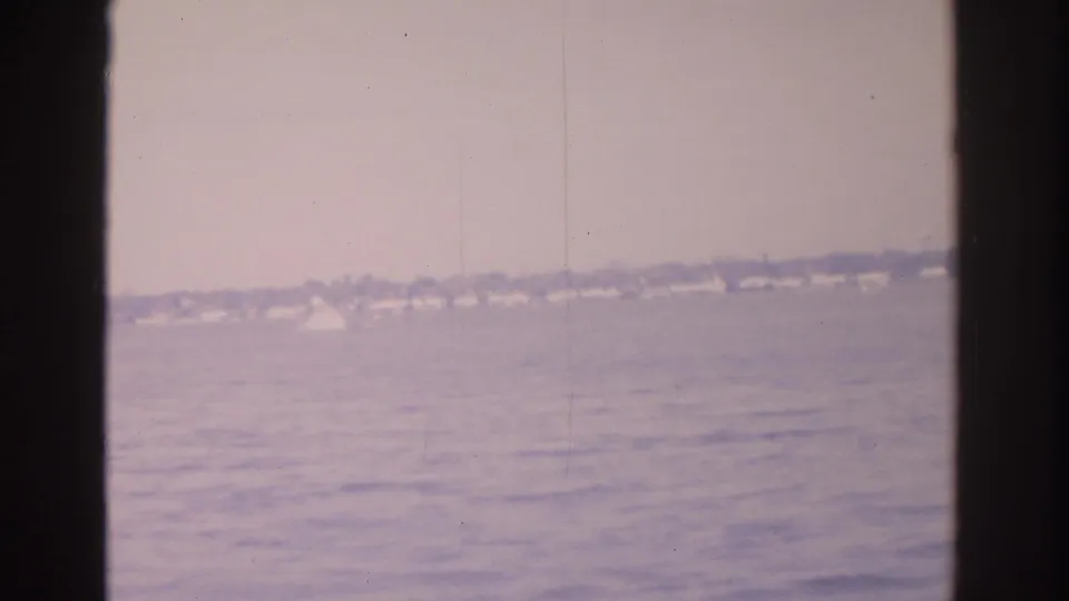 Distant Florida shoreline across rippled water, with homes and trees softened by 8mm film haze.