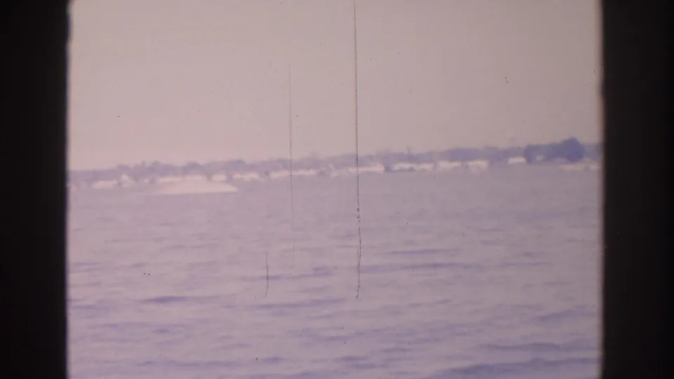 Vintage 8mm view of Florida waterfront homes and trees beyond gently rippled water.