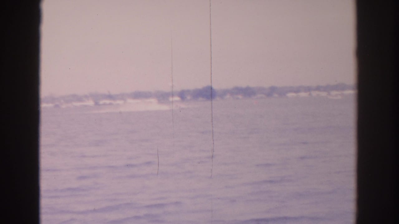 Distant Florida bay shoreline seen across hazy water with dark film borders.