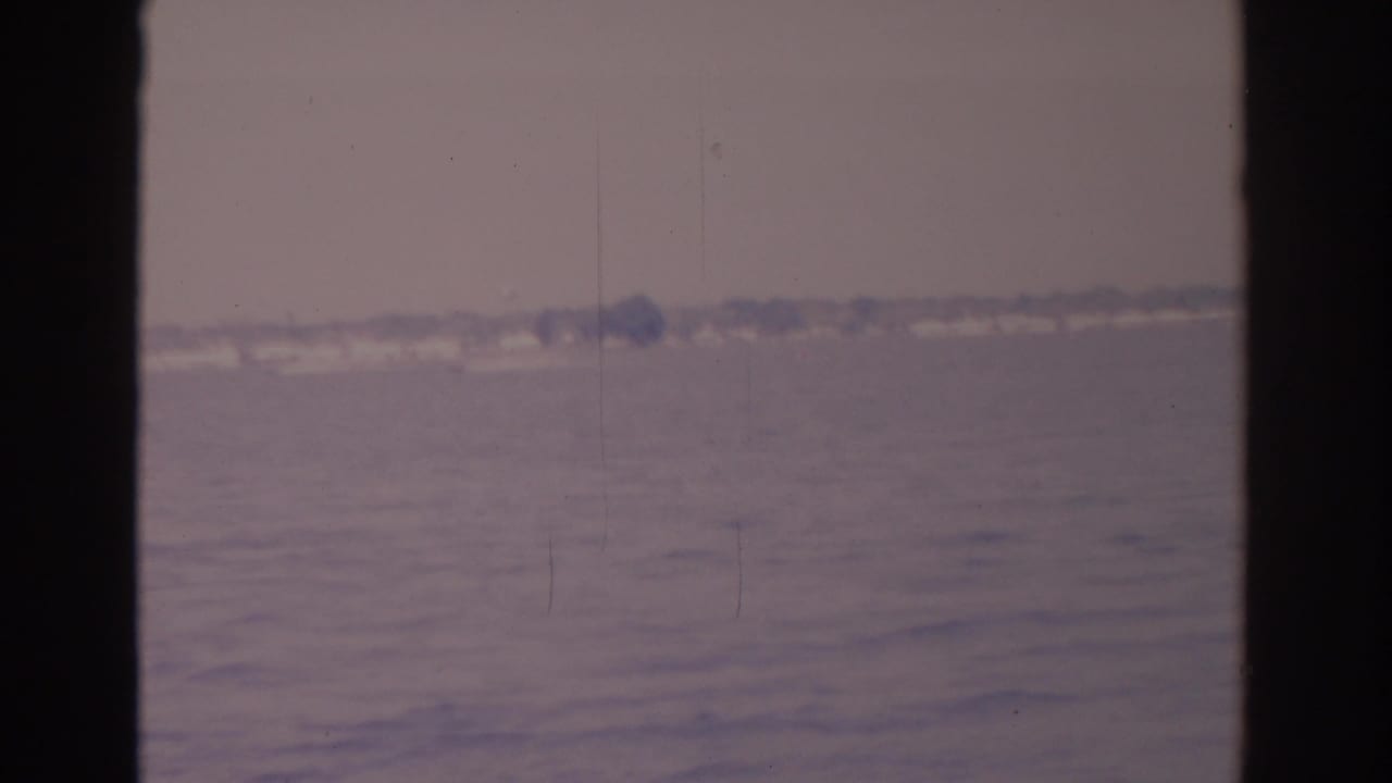 Hazy open water with a distant shoreline seen between dark vertical frame edges.